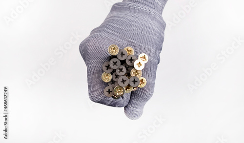 Fototapeta Naklejka Na Ścianę i Meble -  hand in a glove holds a lot of self-tapping screws. Repair