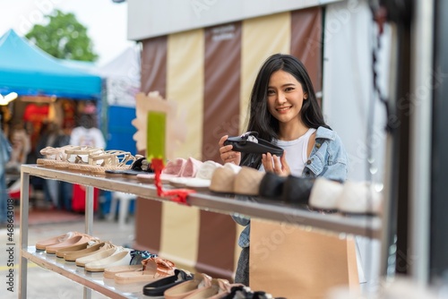 Beautiful asian female young model lady having a solo shopping and stroll walk time by herself and looking through concentratedly some fashion product put on sale at a fashion store in a night market 