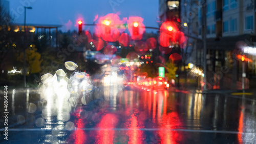 Heavy rain obscured traffic lights and car headlights at a road junction at dusk