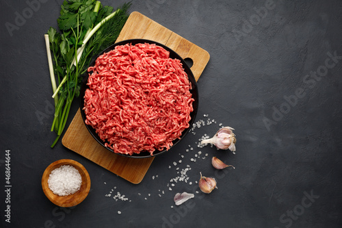 Minced meat, spices and herbs on black background. Copy space for text.