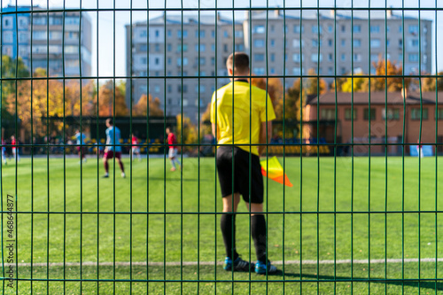 Football stadium fence close up on a sunny autumn day with referee and players in the background