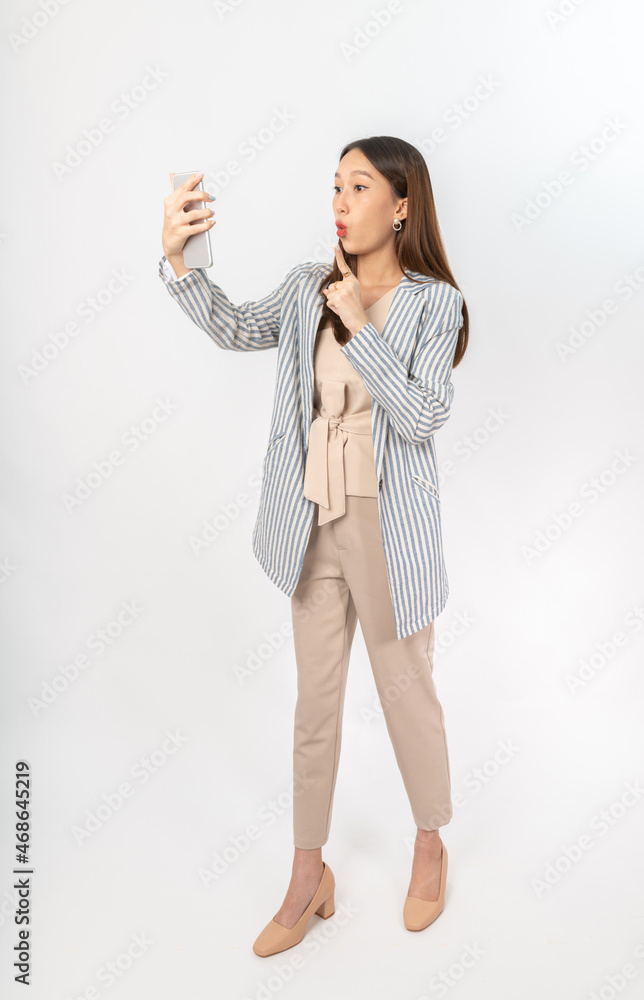 Photograph of a young, beautiful and sexy asian Thai lady model in professional business attire with a mobile phone on hand Photograph of a young, beautiful and sexy asian Thai lady model in professional business attire with a mobile phone on hand