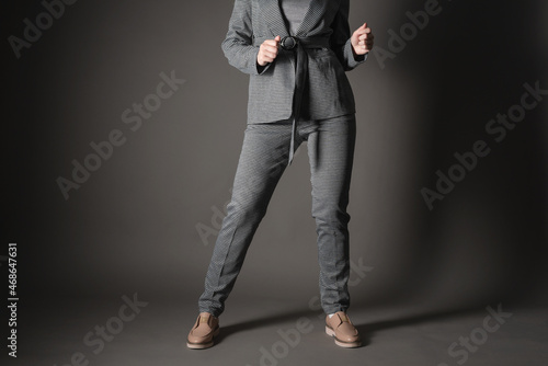 Woman in the gray suit is dancing on the gray background. © Natali