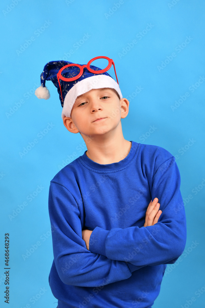 A boy in a blue sweater inflates an orange balloon on a blue background. A boy in a blue sweater inflates an orange balloon on a blue background.
