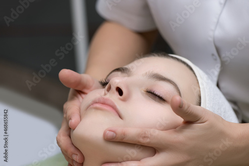 Face massage. Close-up of young woman getting spa massage treatment at beauty spa salon. Spa skin and body care. Facial beauty treatment. Selective focus.