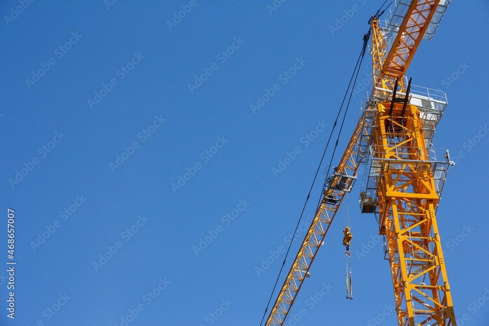 Tower crane on a background of blue sky. Construction crane at a construction site. Heavy Duty Lifting Equipment