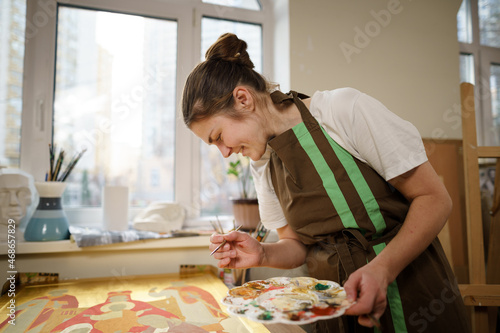 Art, creativity, hobby and creative occupation concept. Bringing creativity to life. Woman painting in art studio. Attractive female artist painting in workshop. Woman hobby, activity, profession