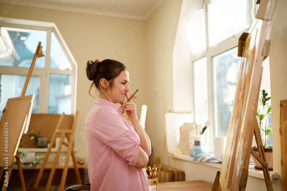 Female artist working in studio. Creative workspace, painting class, easel with canvas, art therapy. Inspiration, creativity, talent, craft concept. Artist studio interior. People, leisure and hobby Female artist working in studio. Creative workspace, painting class, easel with canvas, art therapy. Inspiration, creativity, talent, craft concept. Artist studio interior. People, leisure and hobby