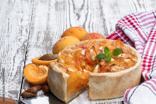 Homemade apricot pie with almonds on white wooden table photo