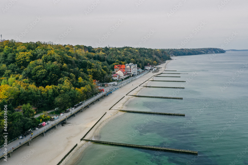 Panoramic aerial view of the Baltic Sea coast and the promenade in the resort town of Svetlogorsk, beach, Waves breaking on breakwaters, Old wooden ridges. Kaliningrad region.