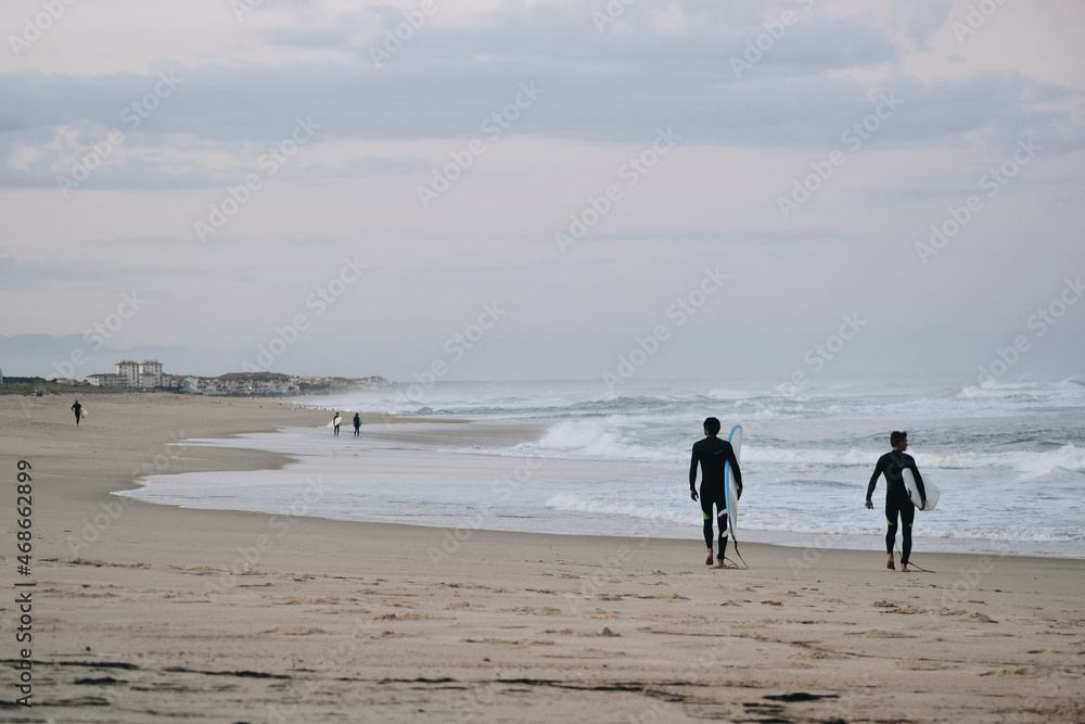 Surfers walking on the beach in the morning
