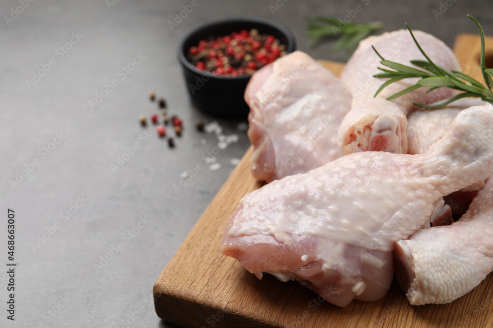 Raw chicken drumsticks with rosemary and spices on grey table, closeup. Space for text