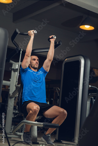 young man exercising lats on machine