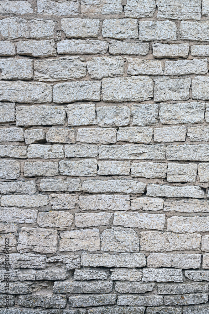 Fototapeta premium old brick wall made of limestone blocks of different sizes as the background