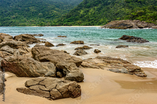 Rocky and deserted beach surrounded by dense and preserved rainforest with tranquil waters and vivid colors in Trindade, Paraty, Rio de Janeiro photo