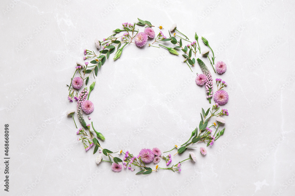 Wreath made of beautiful flowers and green leaves on light grey marble background, flat lay. Space for text