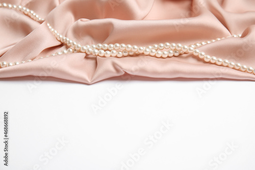 Beautiful pearls and pink silk on white background
