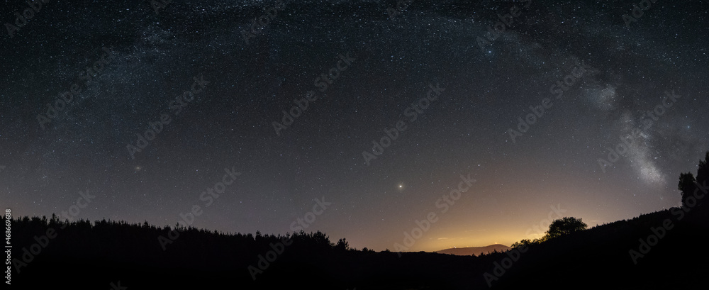Milky Way arc on the top of the mountain and with the lights of Portugal behind