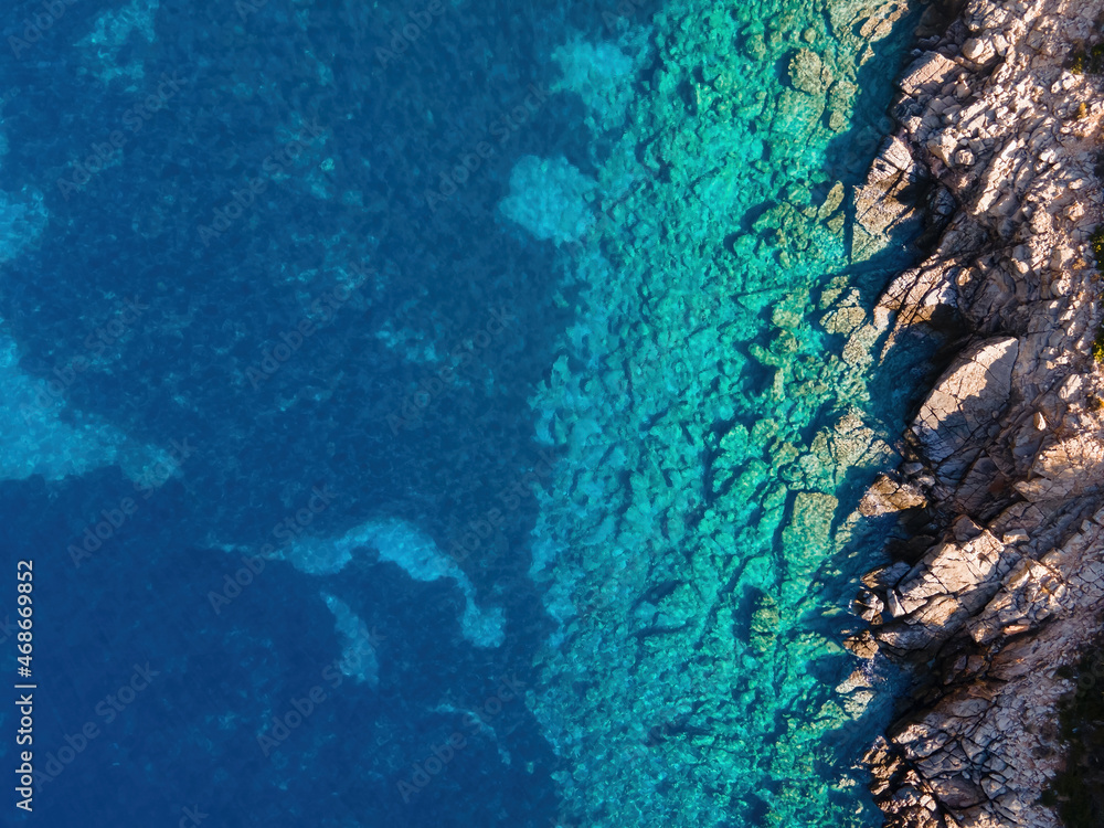 Fototapeta premium Top view of transparent shallow turquoise ocean sea water surface and rock. Aerial top view, Aquamarine background