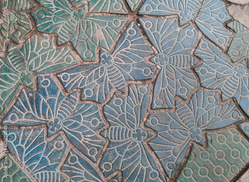 The texture of the old tiles in the shape of butterflies. Beautiful geometric pattern on the road.