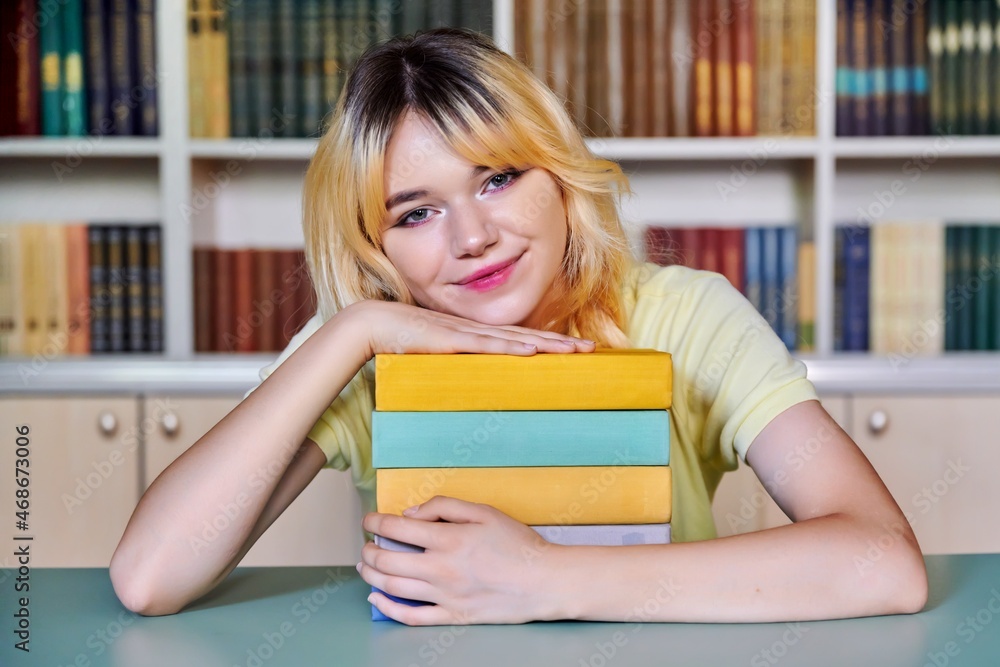 Female teenage high school student looking at camera with books in library Female teenage high school student looking at camera with books in library