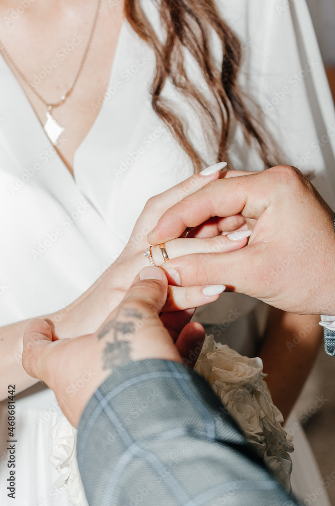 husband puts a ring on his wife's finger at the wedding