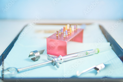 Dental instrument table, endodontic tools, anesthesia syringe, no people, blue background, out-of-focus background