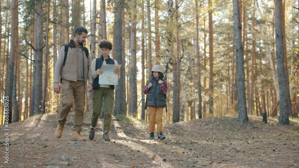 Happy family with kid are walking in forest hiking studying map and talking enjoying escape to woodlands. Active lifestyle and adventures concept. Happy family with kid are walking in forest hiking studying map and talking enjoying escape to woodlands. Active lifestyle and adventures concept.