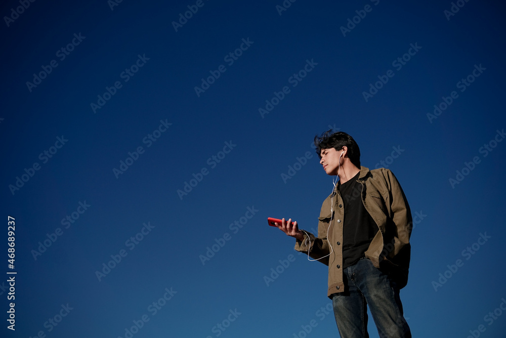 Naklejka premium Joven disfrutando el atardecer escuchando música
