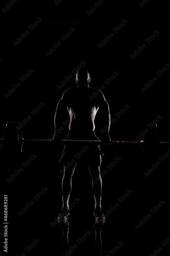 Athlete lifting barbell. Silhouette of a muscular man Athlete lifting barbell. Silhouette of a muscular man