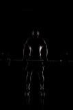 Athlete lifting barbell. Silhouette of a muscular man