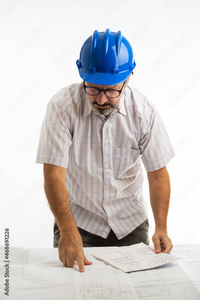 Man wearing protective helmet and analyzing engineering project which is on the table Man wearing protective helmet and analyzing engineering project which is on the table