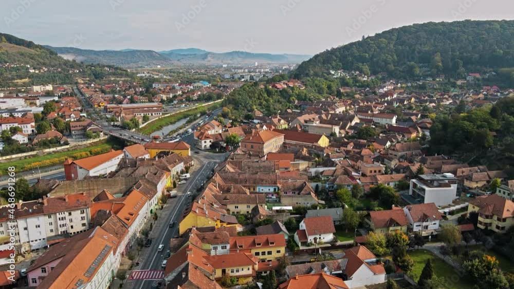 Aerial drone view of Sighisoara, Romania. Roads with cars, river, greenery and buildings