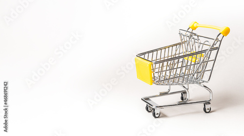 Miniature shopping cart isolated on a gray background with copy space