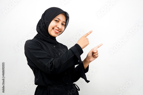 Beautiful young asian muslim woman smiling confident, enthusiastic and cheerful with hands pointing empty space presenting something facing camera isolated on white background, advertising concept