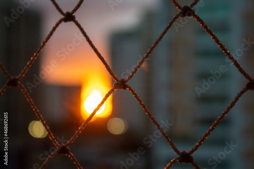 Late afternoon orange sky seen through a barred window