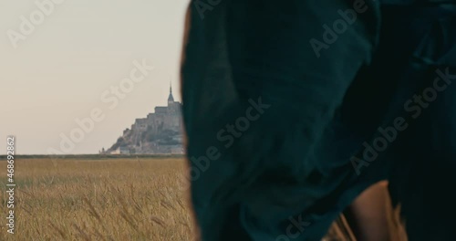 Young woman wearing hat a dress running towards mont saint michel shot in 4k super slow motion 
