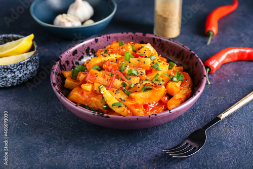 Plate with honey chilli potato on color background