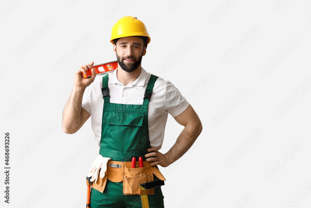 Construction worker in hardhat with builder level on light background