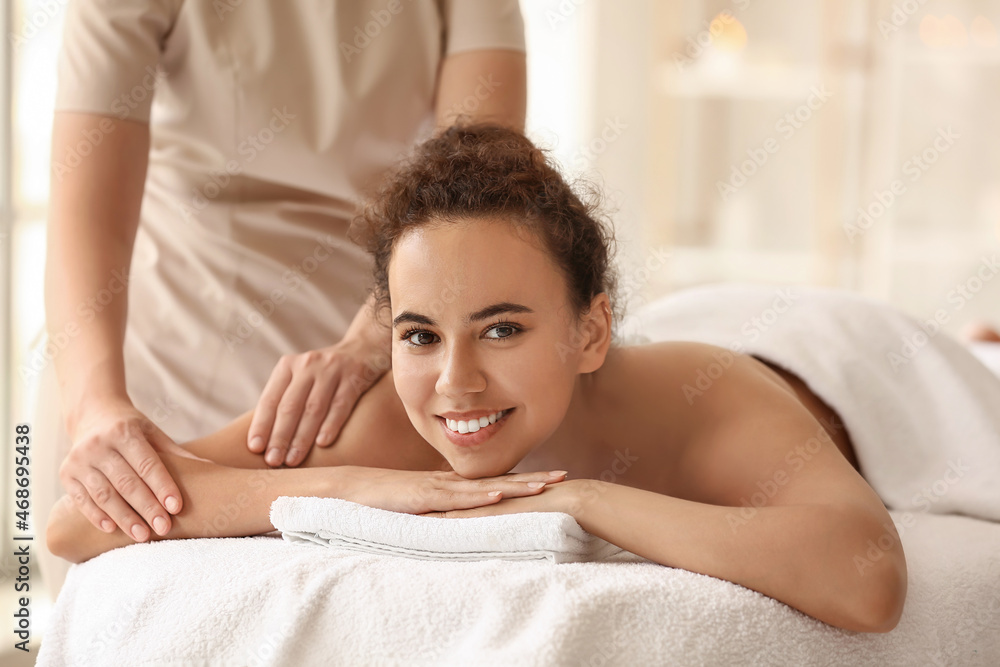Beautiful African-American woman getting massage by therapist in spa salon Beautiful African-American woman getting massage by therapist in spa salon