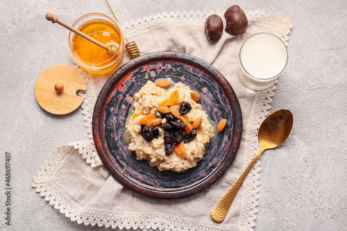 Composition with delicious oatmeal  prunes  dried apricots and almond nuts in plate on light table