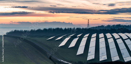 Solar energy park and conventional electricity pylon at sunset,Hampshire,England,UK.