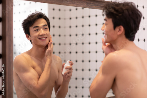 Young Chinese man applying moisturizer photo