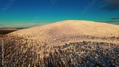 Aerial view of sunlit, snowy Keimiotunturi fell in Lapland - tracking, drone shot photo