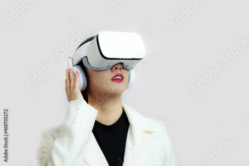 Metaverse VR concepts, asian woman in white jacket wearing virtual reality glasses and looking at something on the white background. 