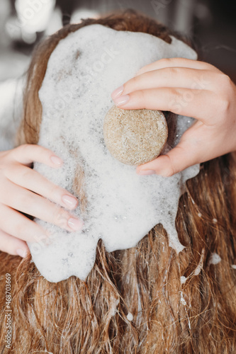 Young woman using natural eco friendly solid shampoo bar. Zero waste and sustainable plastic free lifestyle concept. washing hair with natural shampoo.