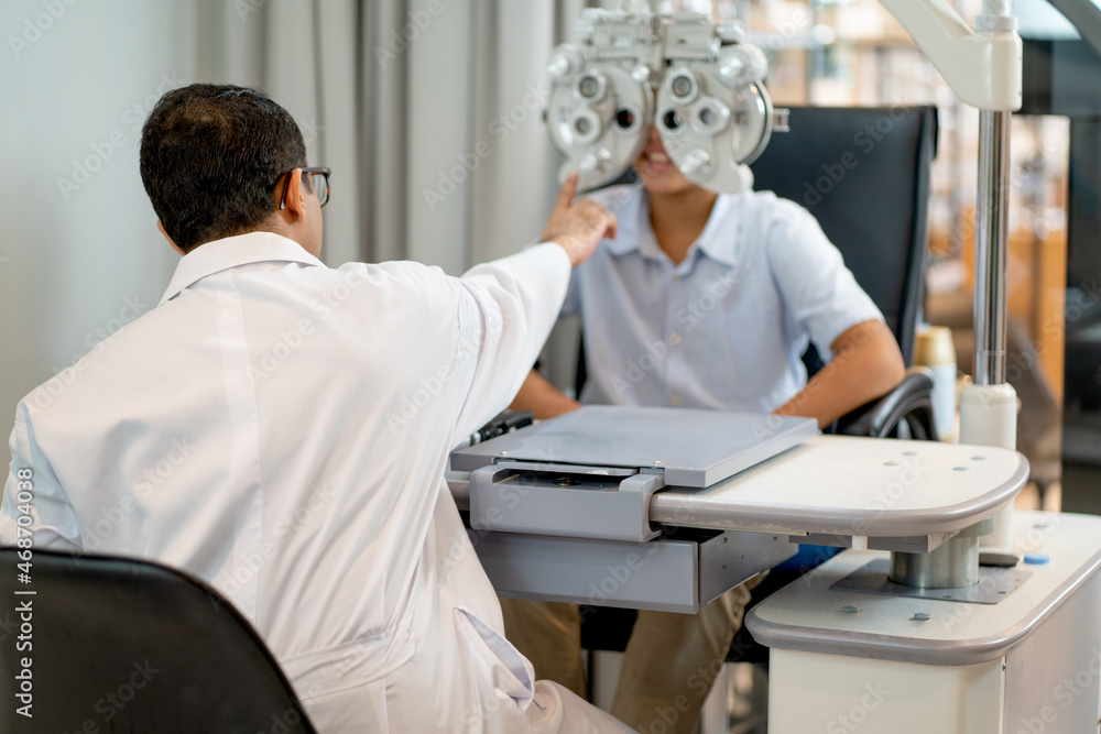 Back of optical staff use machine to measure eyesight of boy in optical shop. Back of optical staff use machine to measure eyesight of boy in optical shop.