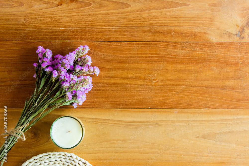 Fototapeta premium A purple flowers on wooden background with candles. 