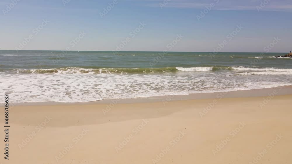 Close up on some waves gently crushing into a yellow beach, camera moving to the right and revealing some footprints in the sand. 4K, 60fps. Close up on some waves gently crushing into a yellow beach, camera moving to the right and revealing some footprints in the sand. 4K, 60fps.