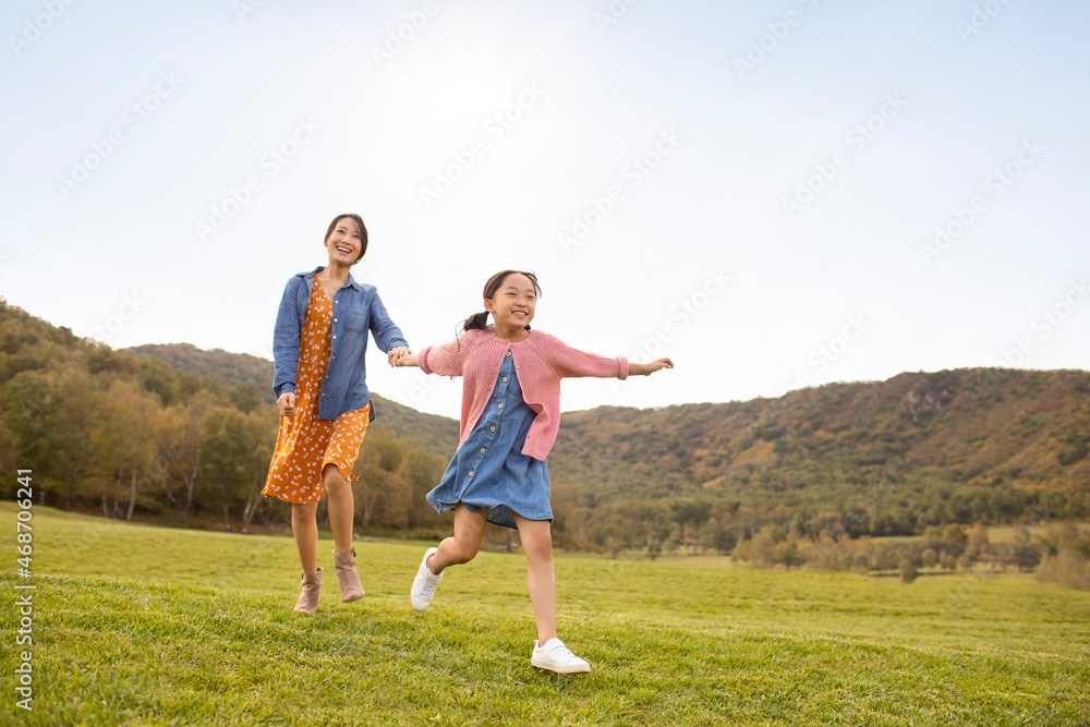 Happy Chinese mother and daughter playing on meadow Happy Chinese mother and daughter playing on meadow